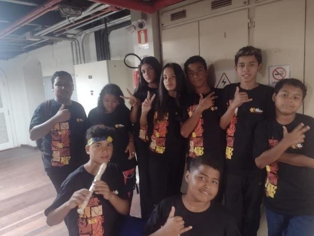 Grupo de adolescentes com instrumentos, em apresentação