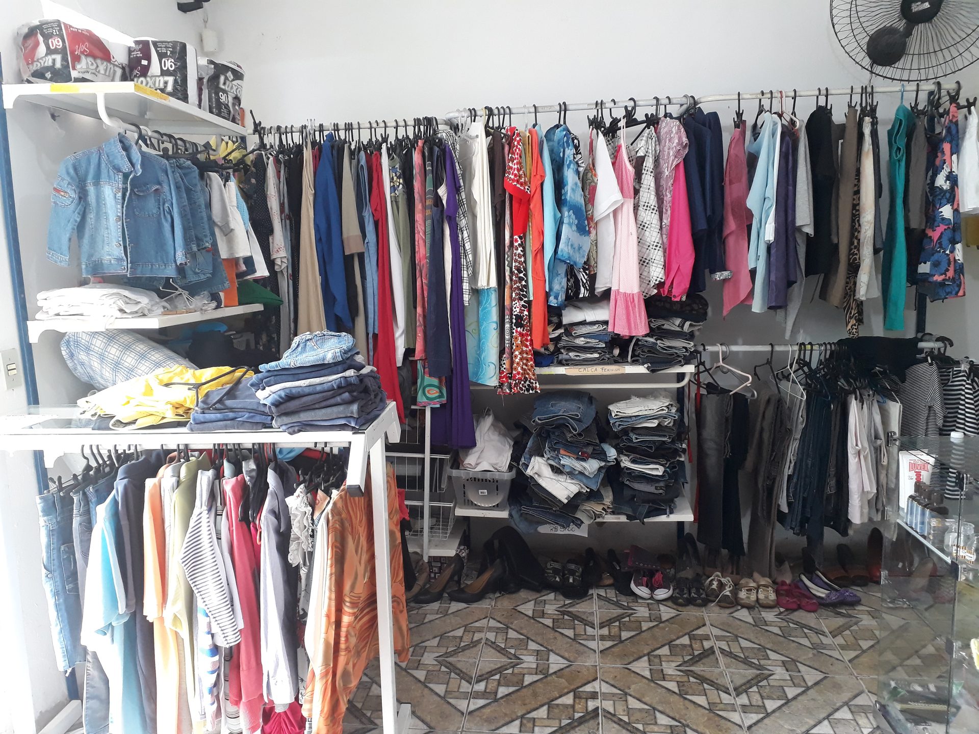 Araras com roupas doadas, organizadas no bazar da instituição