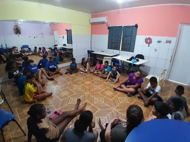 Roda de conversa com crianças e educadores sentados no chão